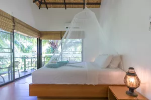 Canopy bed in a bright Anurak Lodge room at Khao Sok National Park, looking out to the jungle through sliding windows