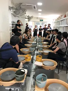 Sesi tembikar roda putar di studio Singapura, dengan pasukan kreatif berkumpul mengelilingi roda seramik — bengkel di Singapura