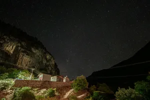 Starry night sky over Shangri-La mountains and valley village rooftops with power lines below at night
