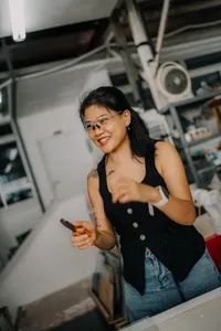 Tan Sock Fong smiles while shaping a glass centrepiece on a workbench at Art Glass Centre, workshops in Singapore