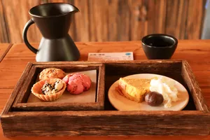 Coffee cupping tray with pastries and black cups beside a small coffee pot at the family-run specialty coffee workshop in Lijiang