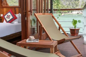 Deck lounge set with a wooden sunbed and small table beside the cabin window, on a boutique cruise in Cat Ba