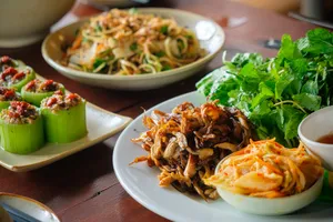 Hanoi lunch spread with bowls of noodles and leafy herbs on wooden tables during an Up Travel Vietnam rare agarwood tour