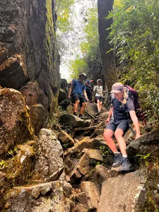 Trekking through a shaded rocky gorge on the Fansipan eco trail near Sapa, with bamboo-lined cliffs on both sides