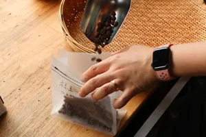 Hands packing freshly roasted coffee into labelled paper bags at Seeker Yunnan Coffee Estate in Lijiang