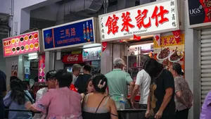 Busier Singapore hawker centre lane with diners queuing in front of street-food stalls under colourful signage — Singapore hidden gems