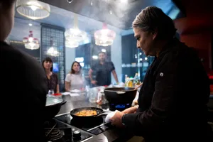 Wok station during a Singapore team local produce cooking challenge, diners and chefs stir simmering dishes — workshops in Singapore