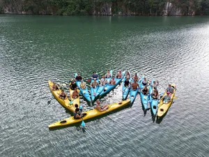 Kayakers in bright yellow boats on Halong Bay, gathered in formation with life jackets for a fun water activity