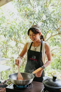 Local Sabahan family cooking in Kota Kinabalu, Borneo—stirring ingredients in a large wok over an outdoor stove