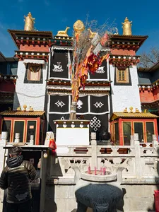 Tibetan Buddhist temple facade in Shangri-La with prayer flags and ornate gateways, bright sky over the courtyard