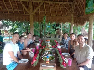 People gathered around a decorated dinner table with plates, drinks and candlelight at Omunity Bali’s open-air meal setting, Bali