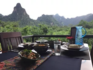 Outdoor dining table with cups and dishes on a rainforest-view terrace during jungle dining in Khao Sok National Park