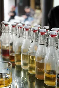 Bottles of local amber drinks and oils on display at a dawn Hoi An market stop during a motorbike trade tour