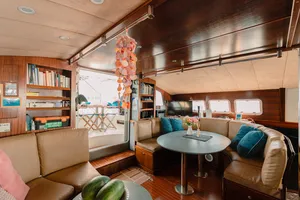 Mawali catamaran lounge in Kota Kinabalu, Sabah, with cushioned seating, a dining table and books for relaxing between stops