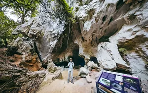 Solo traveller walking along a rocky cave passage in Langkawi, part of an eco discovery combining caves and mangroves