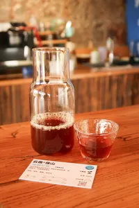 Glass carafe of Yunnan coffee and a tasting cup on a wooden table during a Seeker Yunnan Coffee Estate cupping session in Lijiang
