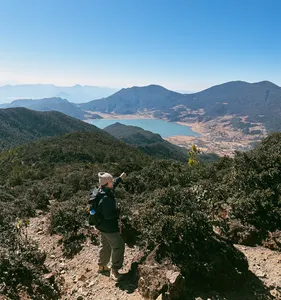 Hiker stands on a high ridge above the valley near Jade Dragon Snow Mountain in Lijiang, guided hike with The Bivou Lijiang