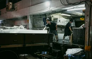 Pemandu Hidden Heritage memimpin melewati lorong belakang yang remang-remang di pelabuhan ikan Jurong, Singapura, sementara para pekerja memilah persediaan