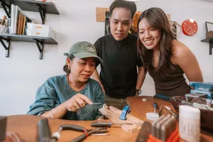 Two people smiling while making couple rings at a workbench in Fat Anvil Studios, a Singapore metalsmithing studio â workshops in Singapore