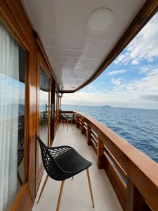 Wooden corridor on deck with a black chair and railing, opening to an ocean view on a 3D2N shared Komodo cruise, Komodo Island