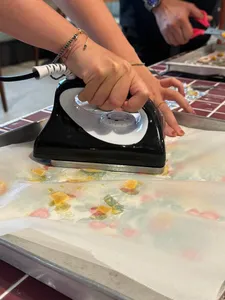 Hands heat-sealing reusable food wrap material with an iron during Agrihome sustainability workshops in Singapore
