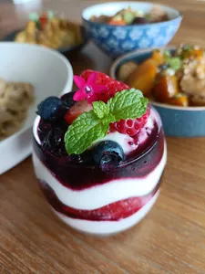 Layered berry and cream dessert in a glass with mint and flowers for TCM-inspired teatime in Singapore, hands-on workshops in Singapore