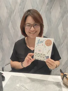 Smiling participant holds her finished vision board for gemstones in Singapore, seated by craft supplies during workshops in Singapore
