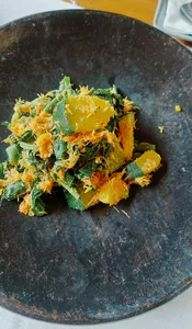 Green and golden shredded vegan topping on a dark plate, prepared in a Traditional Manggarai vegan cooking class in Labuan Bajo