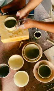 Hands painting and shaping small ceramic bowls with pale green glaze at Ilham Ceramic Studio in Langkawi