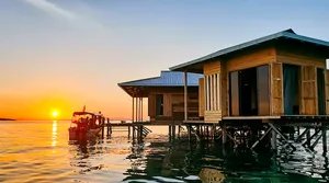 Sunset view of an overwater stilt sea lodge on the pier at Semporna, a calm base for 2D1N diving adventures