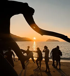Silhouetted group walking along the beach at sunset, with a sail-like hand in the foreground, at Surin Island, Khao Lak