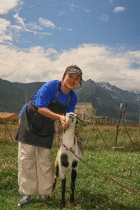 Seeker Yunnan Coffee Estate host smiling while cradling a black-and-white goat on the flowered coffee farm in Lijiang