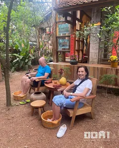 Guests seated at a wooden table during a craft tea moment in an ancient village near Hanoi, surrounded by potted plants