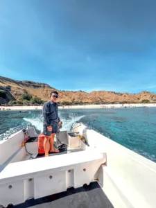Traveller on the bow of a deluxe phinisi in Labuan Bajo with open blue sea ahead, taking in the views on Komodo Island