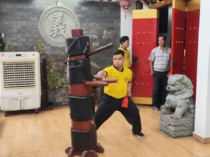Kung fu trainees practising stances with lion-dance drums in an indoor Chinatown hall in Ho Chi Minh City