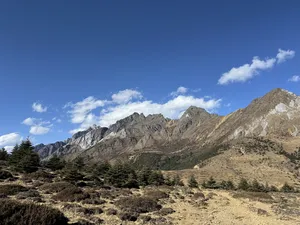 Wide view of craggy peaks and alpine slopes under blue sky during the Jade Dragon Snow Mountain hike near Lijiang