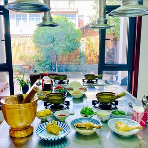 Cooking spread on stoves and table by a window in Lijiang, with pots of ingredients ready for a shared Yunnan meal