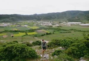Scenic view over fields and the village of Shangri-La from a rocky hillside, with a traveller looking out