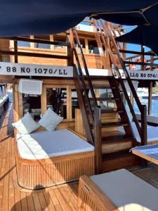 Cushioned daybed lounge under a canopy on a deluxe phinisi deck for relaxing between stops on a cruise to Komodo Island