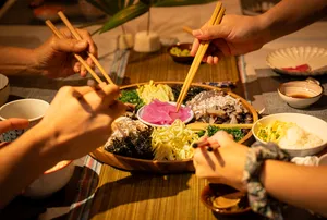 Primateve diners pass chopsticks while sharing grazing platters at a communal table during private dining Singapore