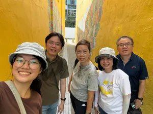 Group posing by a yellow mural wall in Katong-Joo Chiat during the real-life Monopoly experience, Singapore for team building Singapore