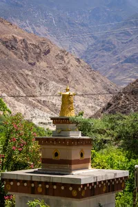 Golden prayer wheel in Shangri-La with sweeping views towards Meili Snow Mountain and misty valley slopes