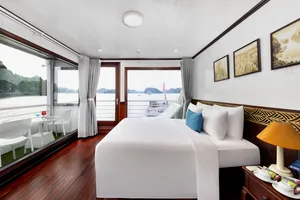 Cabin interior on the Oasis Bay Party Cruiser with a double bed, cushions and large windows viewing the bay during Halong Bay