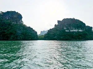 Kilim Geoforest Park sign on karst cliffs across the water, viewed from a Langkawi cruise boat