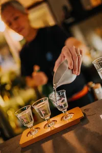 Rare sake tasting in a tucked-away shop in Singapore, SakeMama pours into small glasses on a wooden tray — date ideas Singapore