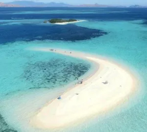 Aerial view of turquoise water and a crescent sand beach with boats and islets on a 3D2N shared Komodo cruise — Komodo Island