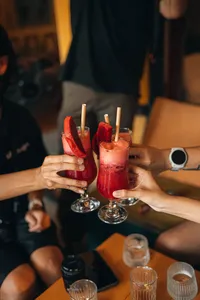 在会安的 Secret Experiences 行程中，朋友们在烛光酒吧里举起红色鸡尾酒轻碰杯，杯边点缀着西瓜角和纸吸管