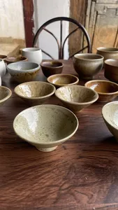 Handmade ceramic bowls and small cups lined up on a wooden table inside an ancient pottery home in Shangri-La, Yunnan