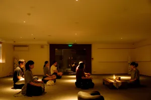 Travellers sit on floor cushions in a candle-lit room for a calm incense tasting during a rare agarwood tour in Hanoi