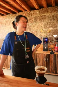 Family-run Yunnan coffee tasting in Lijiang: person in apron pours freshly brewed coffee on a wooden counter